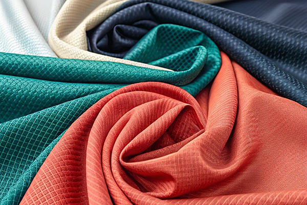 Draped sportswear fabrics in green, orange, navy, and beige with a textured pattern.