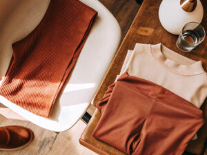 Folded ribbed leggings and sweatshirt with earthy tones on chair and bench.