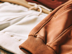 Close-up of beige and brown jogger pants with ribbed cuffs and drawstrings.
