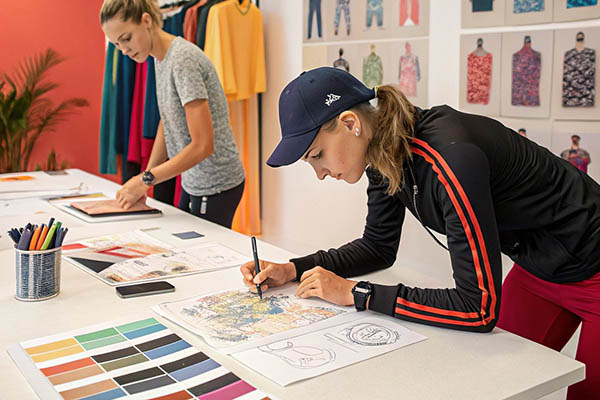Designers sketching clothing concepts with color palettes and fabric samples in a creative workspace.