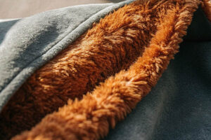 Close-up of a soft brown faux fur lining inside a dark green jacket.