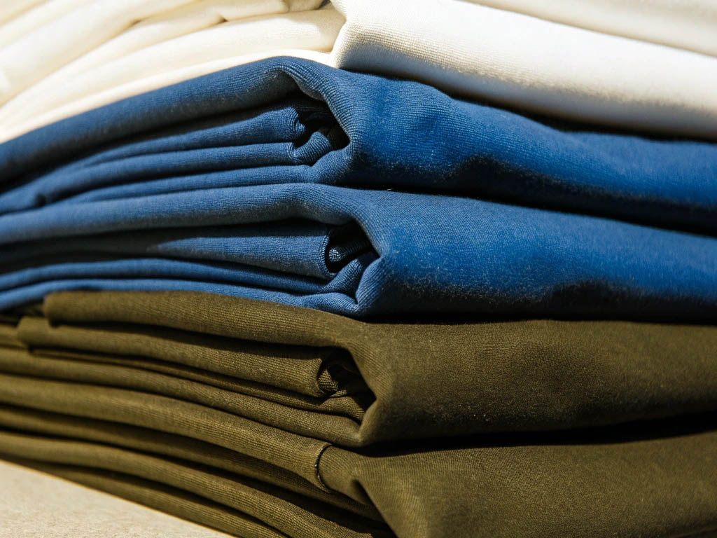Neatly stacked fabric in white, blue, and black colors, highlighting smooth texture and quality.