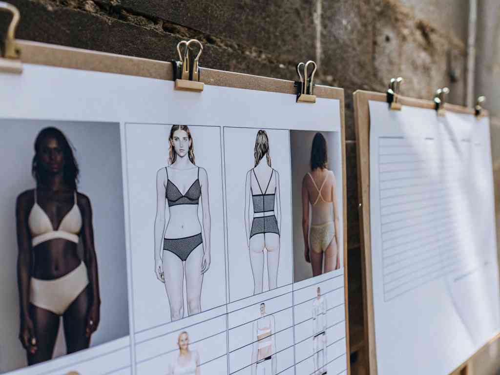 Lingerie design sketches and model photos on clipboards