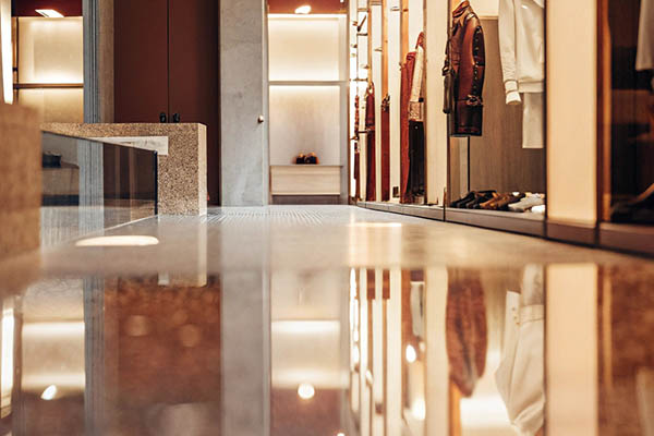 Elegant boutique interior with polished floors, warm lighting, and designer clothing on display.