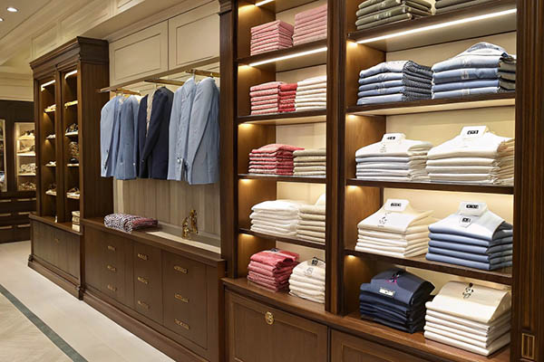 High-end boutique with neatly folded shirts and jackets arranged on elegant wooden shelves.