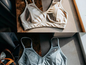 Two sports bras in beige and grey laid flat in soft sunlight.