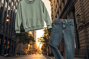 Green sweatshirt and denim jeans floating over a city street at sunset, showcasing a casual fashion look.