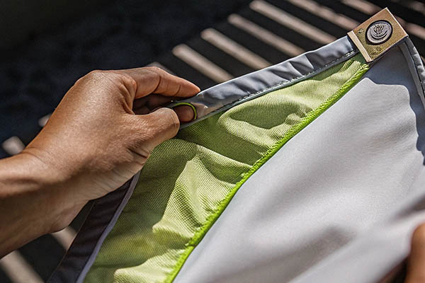 Close-up of a hand holding a garment with green recycled fabric lining.