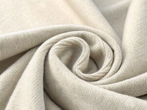 Light beige knit fabric elegantly draped and twisted into a spiral shape.