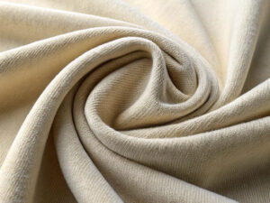 Light beige knit fabric elegantly draped and swirled into a spiral shape.