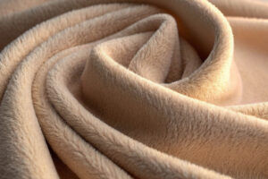 Close-up of beige fleece fabric with a plush texture, artistically folded in soft curves.
