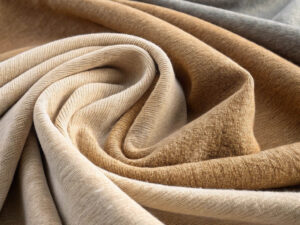 Draped and twisted knit fabric in warm beige and brown tones.