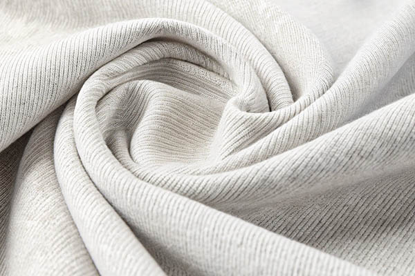 Light gray ribbed fabric elegantly draped and twisted, showcasing its soft texture and fine knit details.