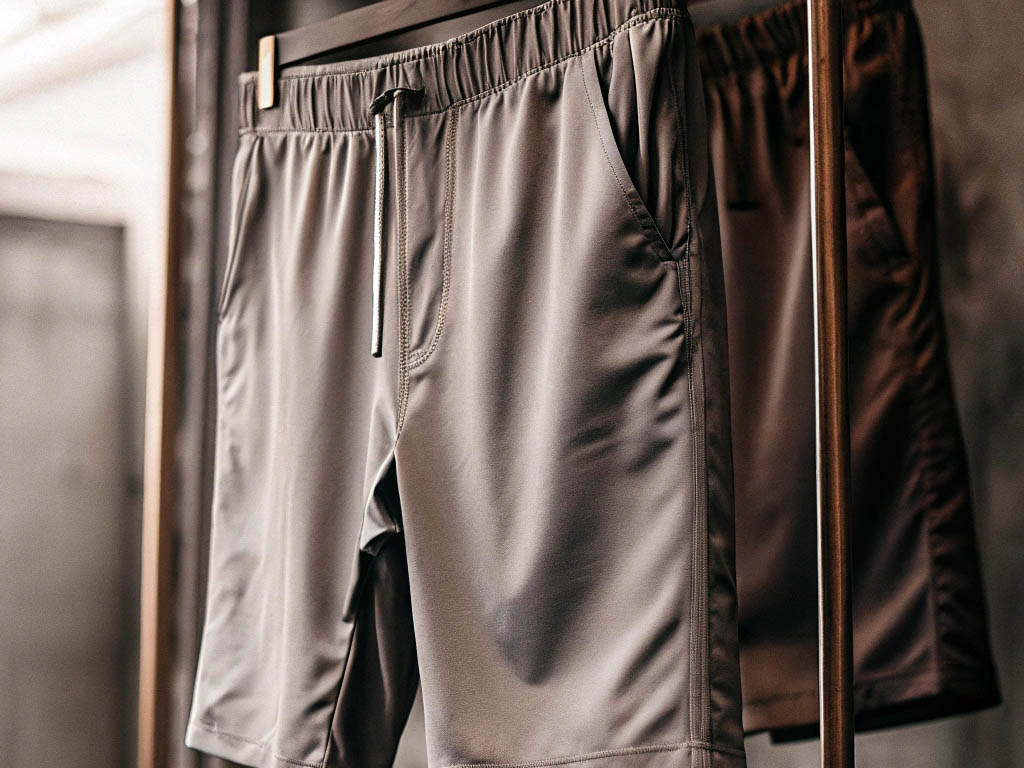 Gray and brown athletic shorts hanging on a clothing rack.