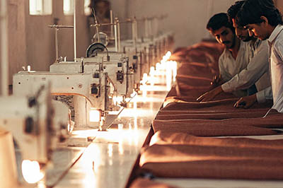 Workers in a textile factory stitching fabric using industrial sewing machines in a production line.