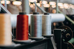 Close-up of colorful thread spools on an industrial weaving machine in a textile manufacturing facility.
