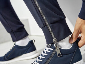 Close-up of navy jogger pants with ankle zippers, paired with matching sneakers.