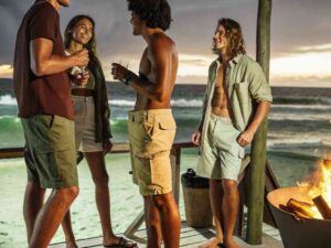 Group of friends by beach firepit wearing summer outfits