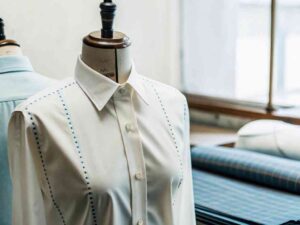 Cream shirt with blue fitting marks on mannequin in fabric workshop.