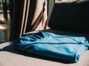Folded blue hoodie on couch in sunlight