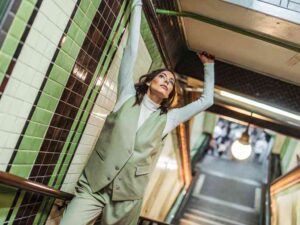 Woman in green suit posing in tiled stairwell