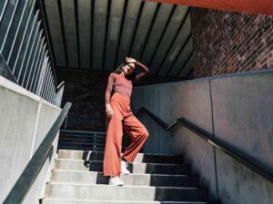 Woman in rust-colored outfit standing on stairs.