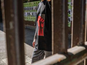 Person wearing black t-shirt with red fist graphic behind bars