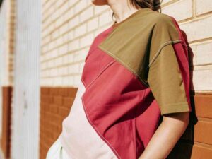 Woman in red and green top standing by brick wall