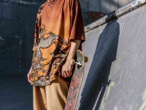 Skater in dragon print shirt holding skateboard