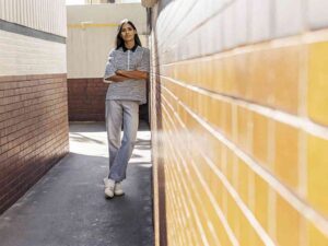 Woman in striped polo and jeans in alley.