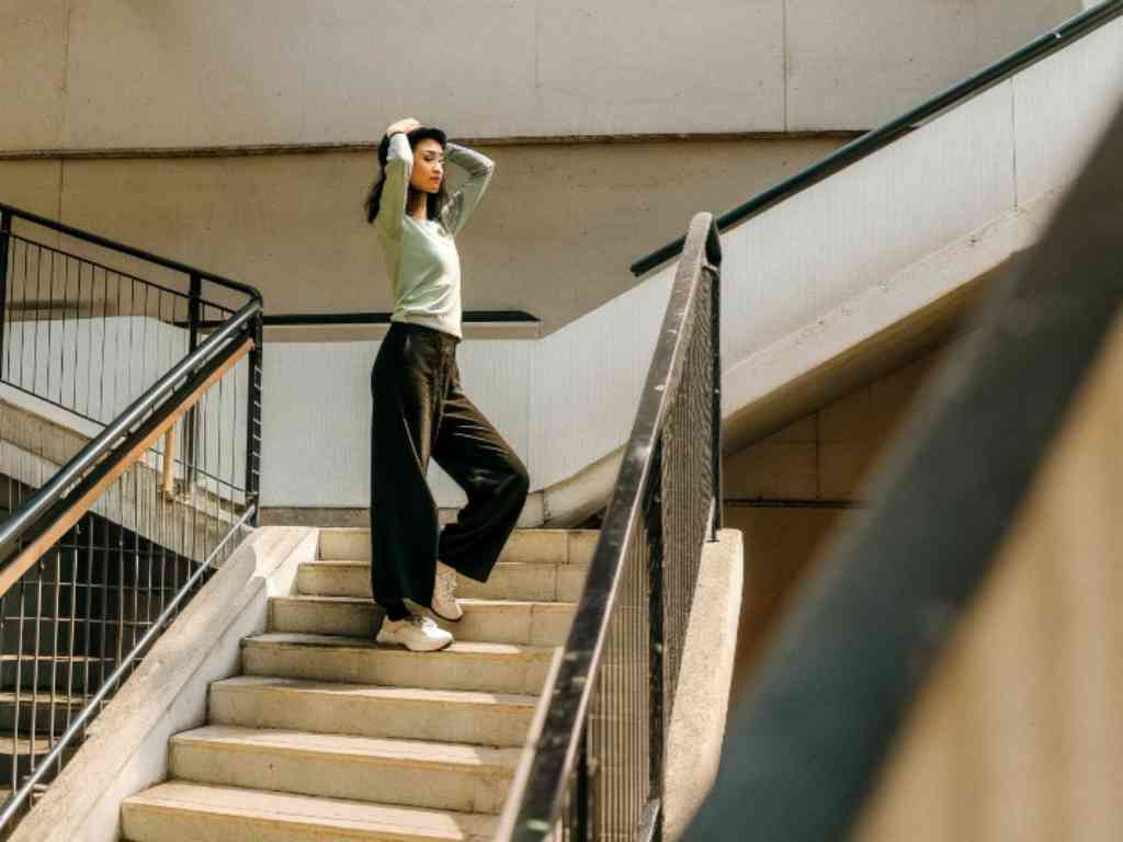 Woman in mint top and wide-leg pants on staircase.