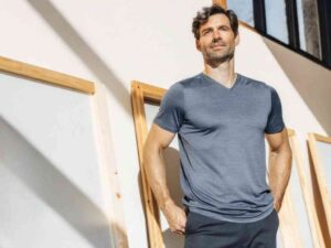 Man in blue V-neck t-shirt standing in natural light.