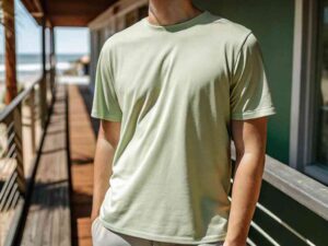 Man wearing light green crew neck T-shirt on boardwalk by beach.