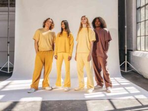 Group of models wearing colorful lounge sets in sunlit studio.