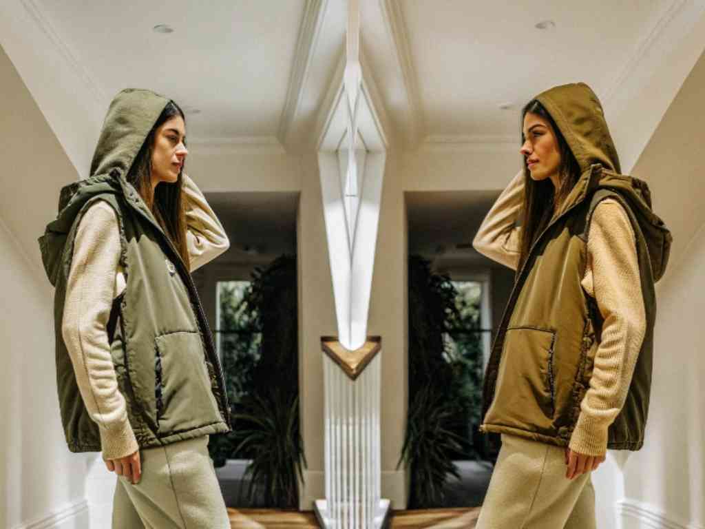 Woman in green puffer vest and hoodie in hallway