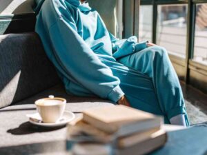 Person in blue sweats relaxing on couch with coffee