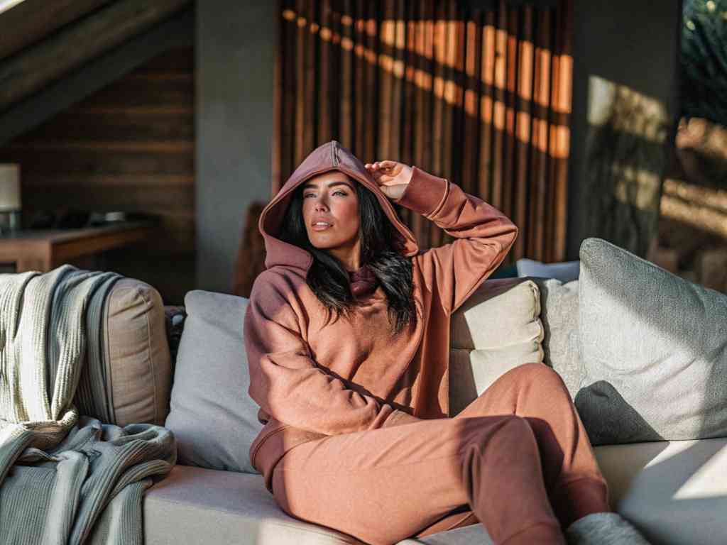 Woman in rust hoodie set lounging in cozy cabin interior