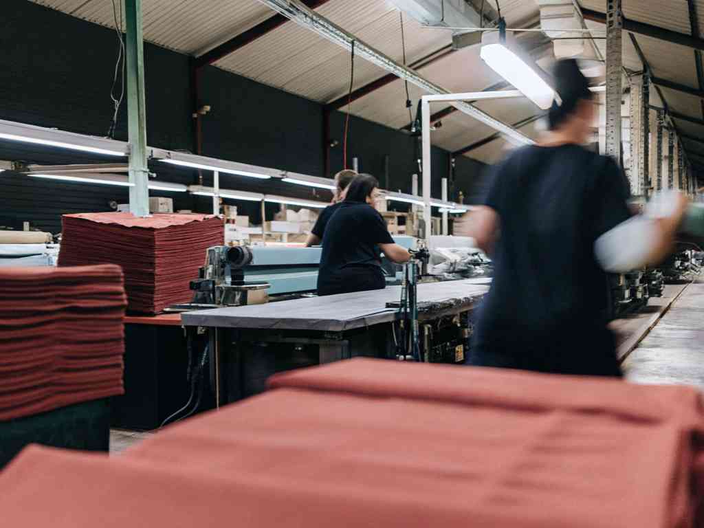 Workers processing red fabric stacks in a textile factory