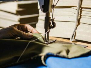 Close-up of sewing machine stitching green fabric in bright light