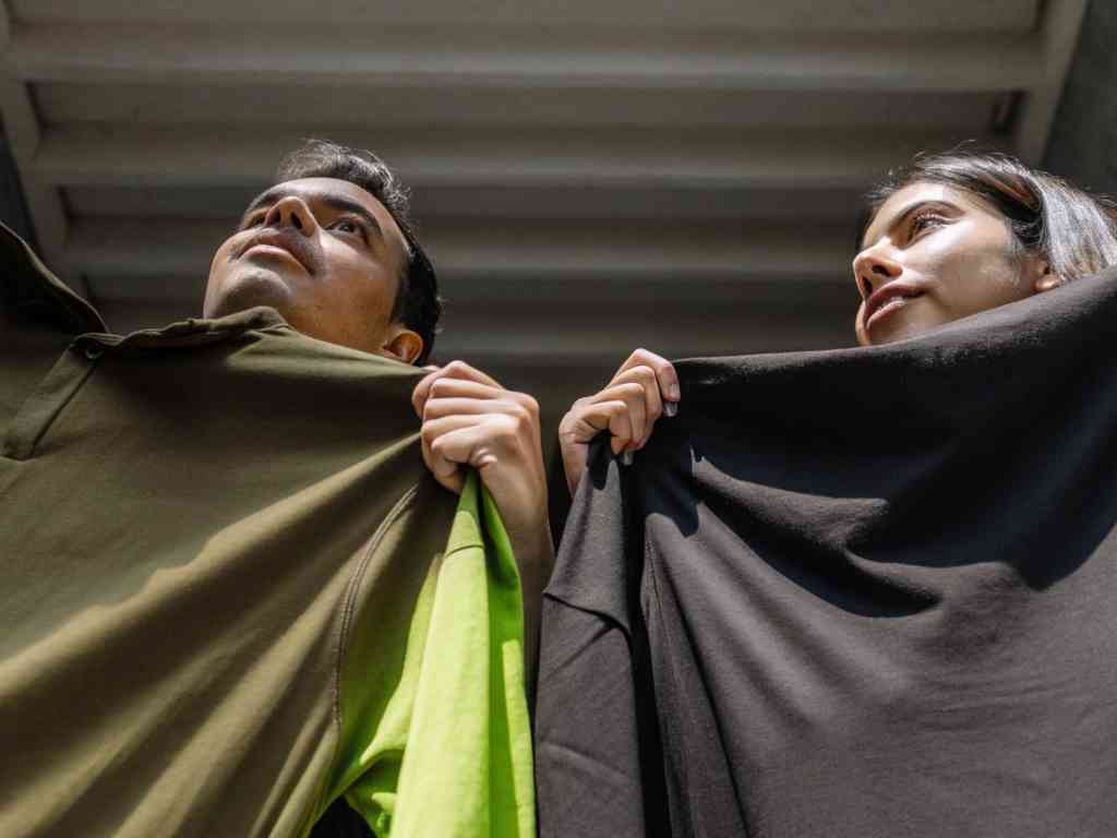 Man and woman holding olive and black fabric under light.