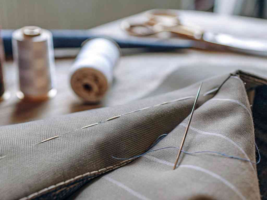 Hand-stitching a pinstripe fabric with needle and blue thread