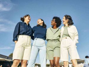Four diverse women laughing in coordinated pastel outfits