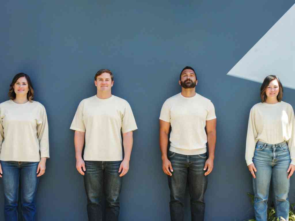 Four people wearing matching neutral tops and jeans.
