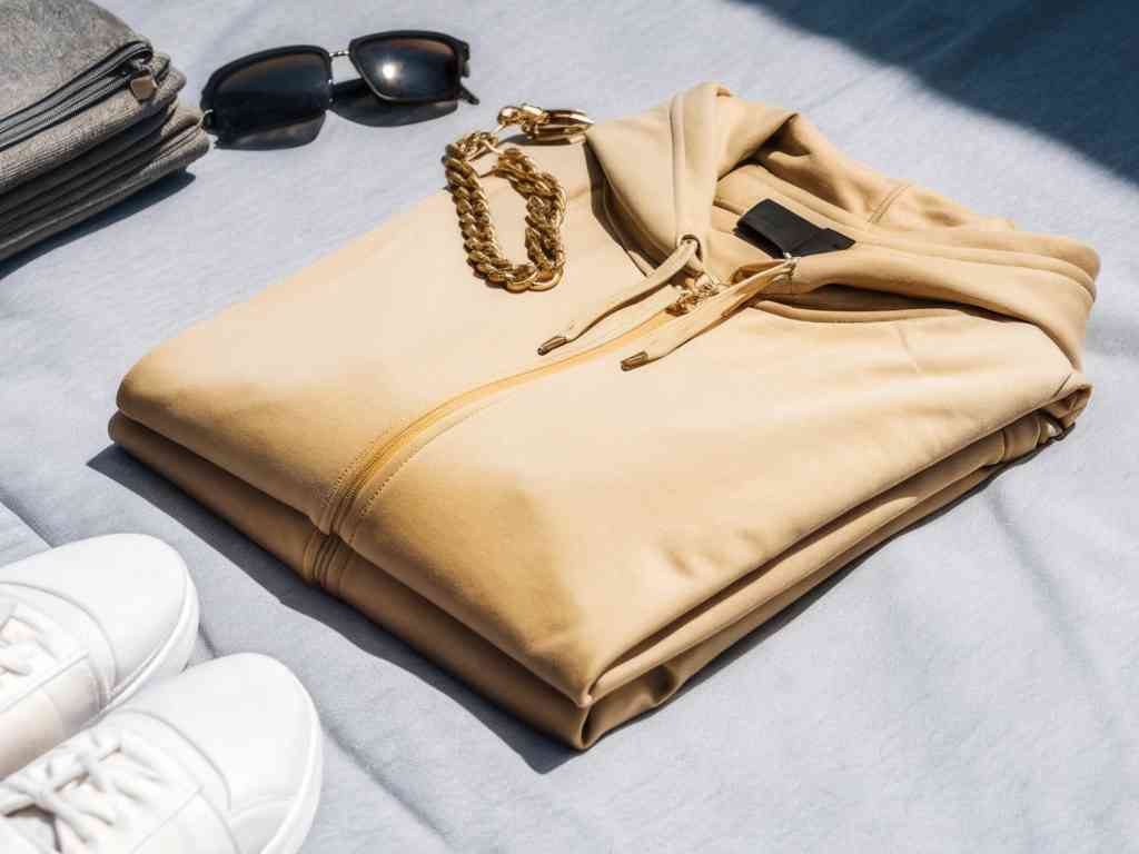 Folded tan hoodie with gold chain and sunglasses