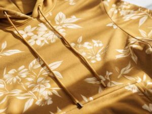 Close-up of mustard yellow floral hoodie under sunlight.