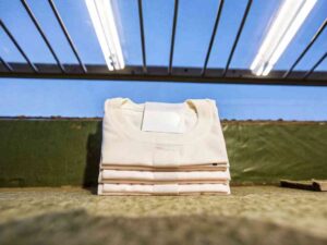Folded white T-shirts stacked under ceiling lights