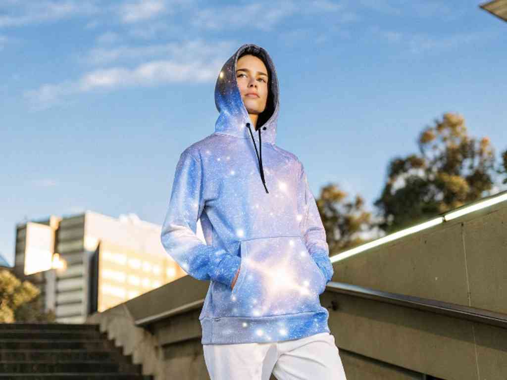Model wearing galaxy-print hoodie standing confidently outdoors.