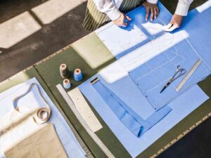 Tailor working on blue fabric patterns with measuring tools