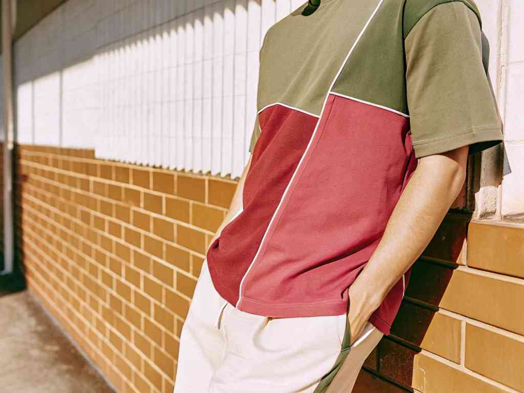 Man in color-block T-shirt leaning on brick wall