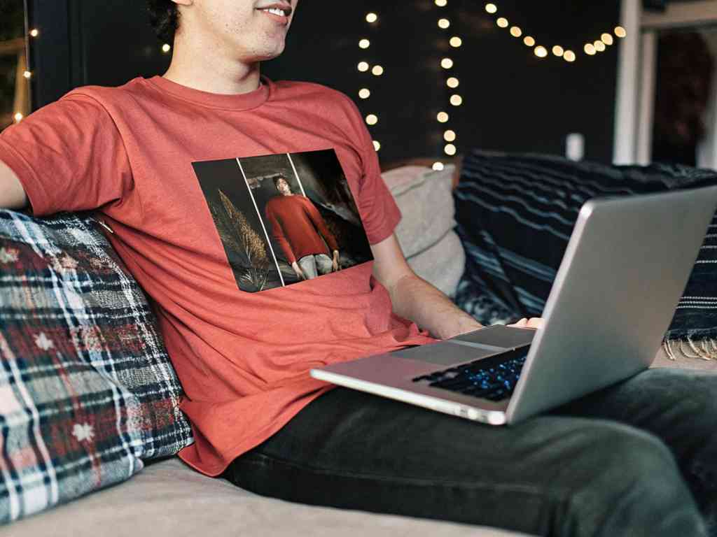 Man wearing red graphic tee relaxing with laptop